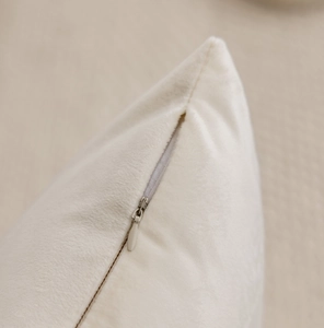 Detail of invisible zipper and soft beige plush texture on luxury decorative pillow cover