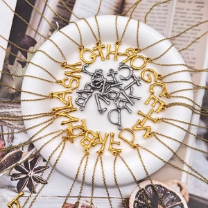 Pendenti con lettere retrò texture bambù in oro e argento su uno sfondo naturale chic