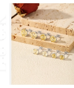 Detail of multi-size yellow gemstone earrings with silver prong settings on stone