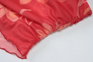 Détail de robe en tulle rouge à fleurs avec bords ondulés et texture froncée