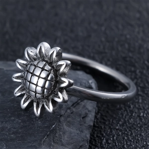 Macro shot of antique silver sunflower ring detailing on a black textured stone surface