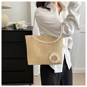 Detail of woven straw tote bag featuring white cotton rope handle and daisy flower accent