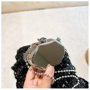 Detailed macro view of the shiny silver mini metal bag featuring a long ball chain strap