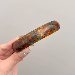 Detail of tortoiseshell spring hair clip shown on hand with elegant resin finish