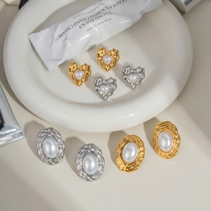 Flat lay of vintage gold and silver oval heart stud earrings with pearls on a white plate