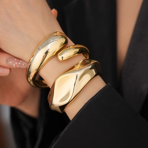 Detail shot of chunky gold irregular open bangle with polished liquid metal finish