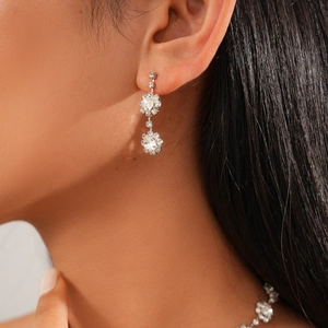 Detailed close-up of silver-tone floral earrings with sparkling crystals on model