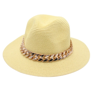 Détail d'un chapeau de paille orné d'une large chaîne métallique en or rose chic