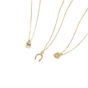 Three gold necklaces featuring cat eye stone teardrop, diamond horseshoe and floral pendants