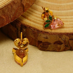 Pink heart-shaped fruit studs with green leaves on a natural wood surface background