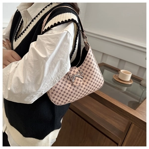 Detail of light beige crescent bag featuring a silver bow clasp and logo patterns