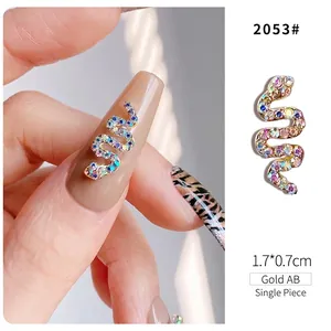 Macro detail of snake-shaped nail charm in Gold AB with colorful rhinestones, 1.7x0.7cm