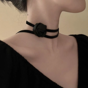Detailed close-up of a black velvet choker necklace featuring a delicate fabric rose