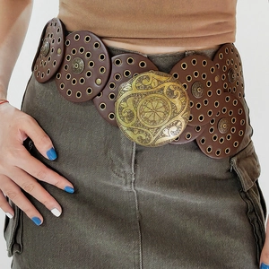 Detail of vintage brown leather belt featuring gold eyelets and carved floral buckle