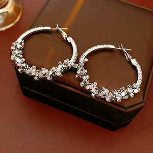 Gros plan de boucles d'oreilles créoles argentées serties de strass sur boîte à bijoux