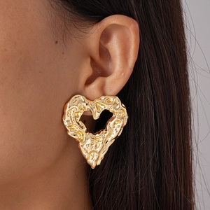 Vintage gold hollow heart earrings with textured metallic finish on model ear