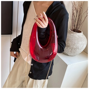 Detail of red acrylic U-shaped evening clutch bag with gold chain strap on display
