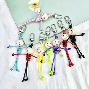 Detailed view of colorful woven doll keychains with smiling wooden bead heads