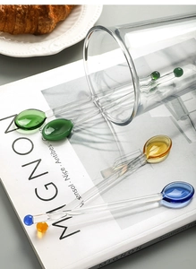 Detailed view of colorful glass heart stirring spoons for coffee and juice on a magazine