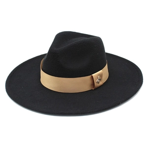 Detail of a black wide brim wool fedora with gold satin ribbon and a small bee brooch