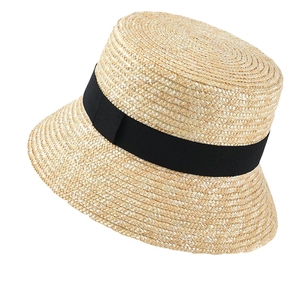 Detailed view of natural straw bucket hat with black ribbon and woven texture