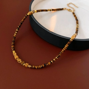 Detail of square tiger eye stone necklace with gold beads on a dark tray