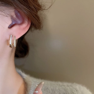 Close-up of elegant double-row U-shaped gold earrings with mother of pearl and cubic zirconia