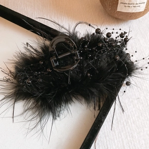 Detail shot of vintage black bow hair claw with elegant feathers and glossy beads