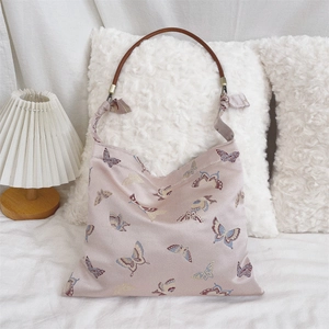 Detail of a pink jacquard shoulder bag with butterfly patterns and brown round handle