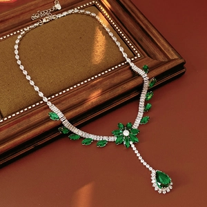 Detailed view of silver flower necklace with emerald green stones on vintage background