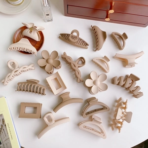 Flat lay of matte nude claw clips set in various geometric shapes on a white desk