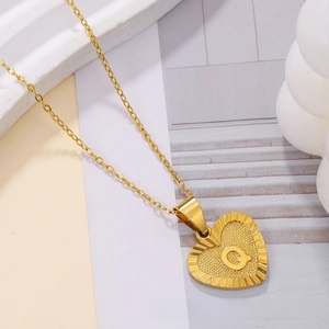 Detailed close-up of golden heart pendant with engraved letter Q on a fine chain