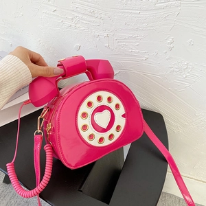 Detail of creative vintage telephone shaped crossbody bag in glossy magenta patent leather
