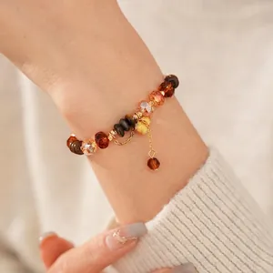 Bracelet œil de tigre avec perles ambrées et pendentif gourde dorée au poignet