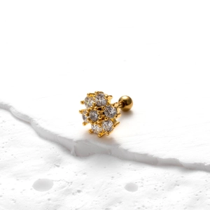 Macro view of gold flower cartilage stud with sparkling cubic zirconia on a stone surface