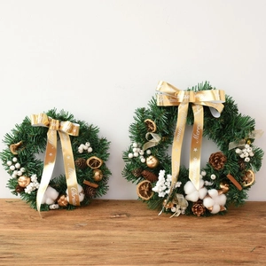 Handmade Christmas wreath with pine cones, dried oranges and cotton on wooden desk