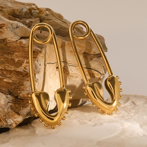 18k gold-plated heart safety pin earrings in stainless steel on a textured rock base