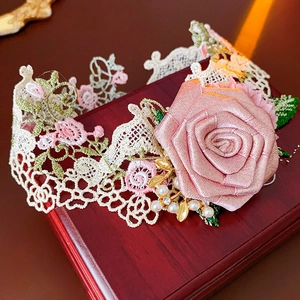 Detailed close-up of beige lace leg garter with large pink fabric rose and pearls