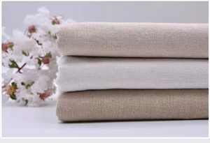 Detailed view of folded linen fabric in beige, white and light brown showing natural texture