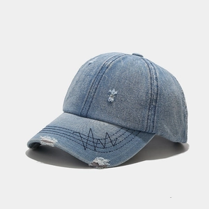 Detail of distressed light blue denim baseball cap with black heartbeat stitching on brim