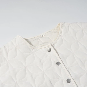 Macro detail of white quilted jacket showing round neck, silver snaps and size S tag