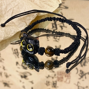 Adjustable black cat charm bracelet with tiger eye beads on traditional background