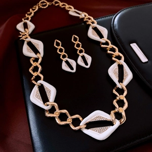 Close-up of geometric white enamel jewelry set with diamonds on red silk backdrop