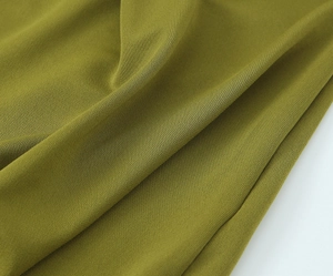 Dettaglio del tessuto dell'abito verde oliva con trama a maglia fine e morbido drappeggio
