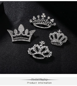Detailed view of four silver crown brooches with sparkling rhinestones on black background