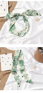 Detail of green and white floral silk scarf with letter B tied in an elegant bow