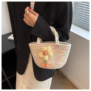 Detail of woven cotton rope handbag with floral charms held by a model in black blazer