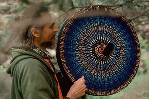 Macro detail of shaman drum featuring intricate blue and orange mandala patterns and beater
