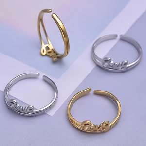 Detailed close-up of gold and silver stainless steel Love letter rings on geometric background