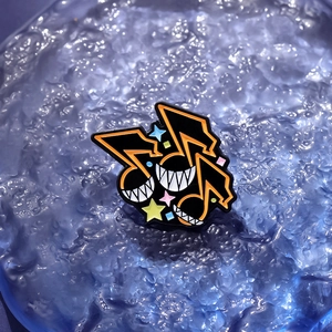 Détail d'un pin's émaillé anime avec notes de musique sur fond bleu texturé